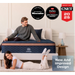Two people on a blue Aurora mattress with awards displayed above them