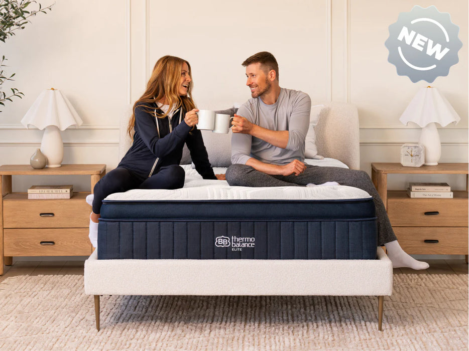 Couple sitting on a thermo balance mattress in a bedroom.